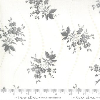 a white and grey floral print fabric with small flowers on the side, in front of a ruler