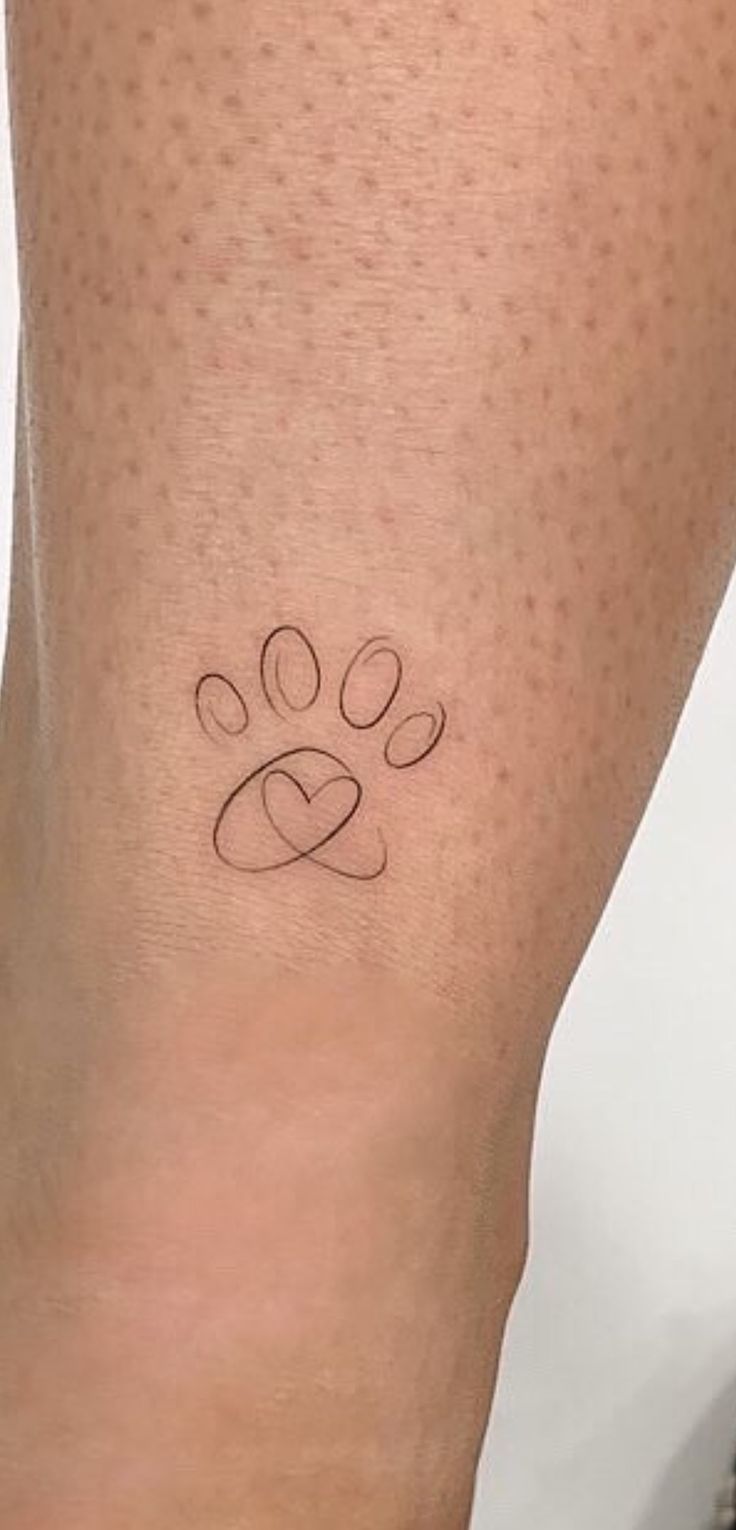 a small paw tattoo on the leg of a woman's legs, with hearts and an interlocked heart