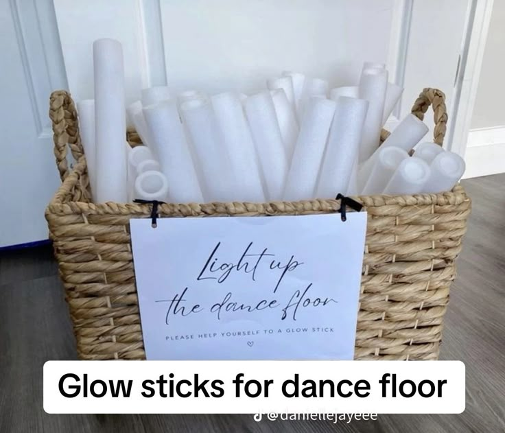 a basket filled with white candles next to a sign that says glow sticks for dance floor