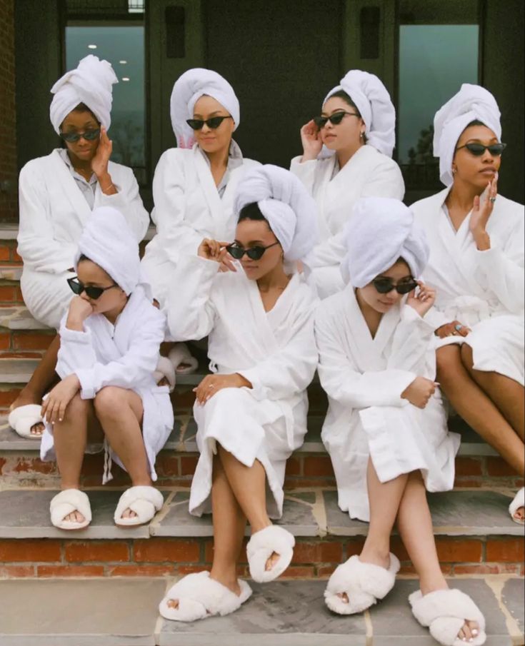 a group of women in white robes sitting on steps with their hands up to their ears