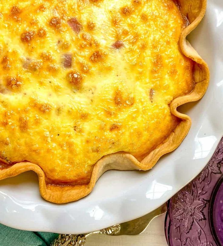 a baked dish on a white plate next to purple plates and utensils,