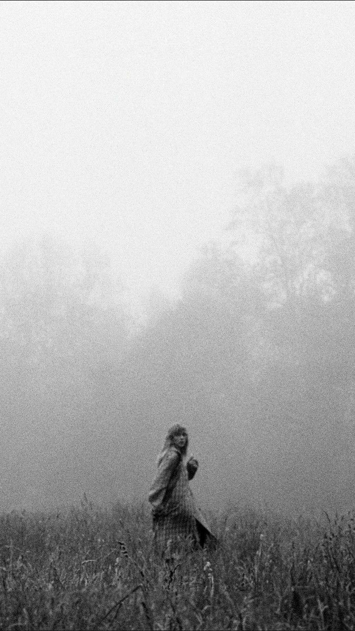 black and white photograph of a woman in a foggy field