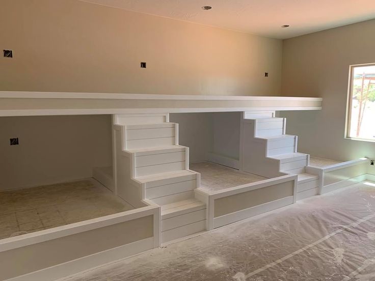 an empty room with white stairs and windows