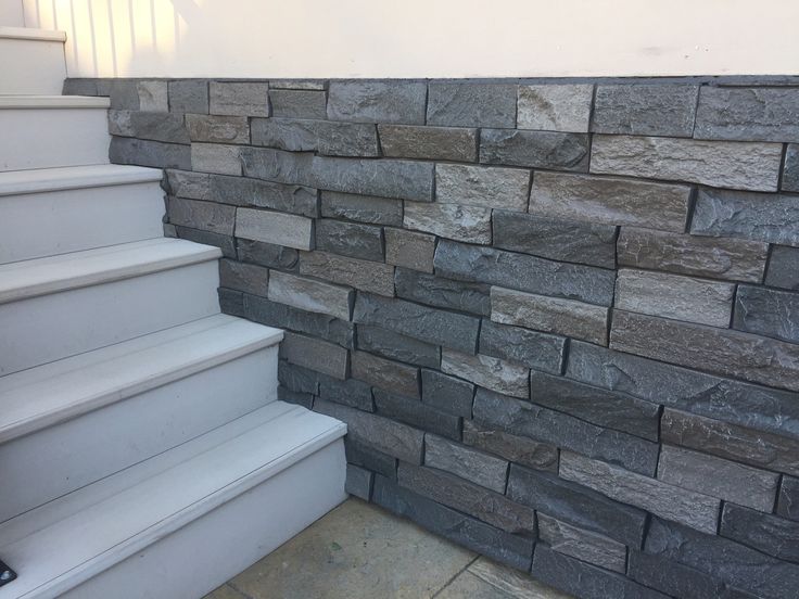 a stone wall next to some white stairs