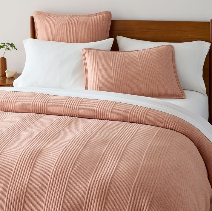 a bed with pink comforter and white pillows