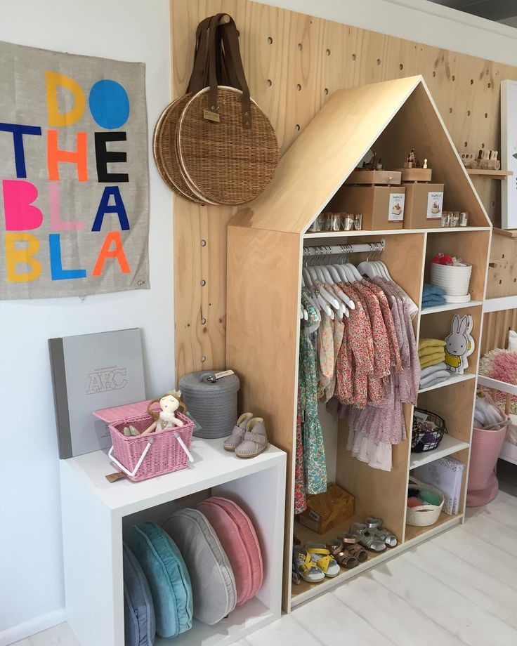 a child's clothing store with wooden shelves and baskets on the wall next to it