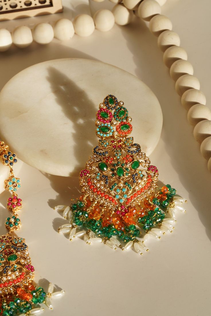 Elevate your festive attire to dreamy perfection with the Sarah - Chandelier Earrings & Maang Tikka Set, an embodiment of grandeur and allure. This exquisite earrings & maang tikka set is meticulously embellished with the splendor of multi-color stones and embellishments, adding a touch of magic to your look. The set includes a pair of stunning chandelier earrings and a maang tikka, each designed to captivate. With an approximate earring length of 3.5 inches, they are a symbol of elegance and op Maang Tikka Set, Stunning Chandelier, Festive Attire, Accessories Ear, Ear Chain, Chandbali Earrings, Maang Tikka, Festive Look, Color Stones