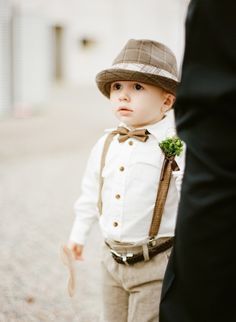 a little boy wearing a hat and bow tie standing next to a man in a suit