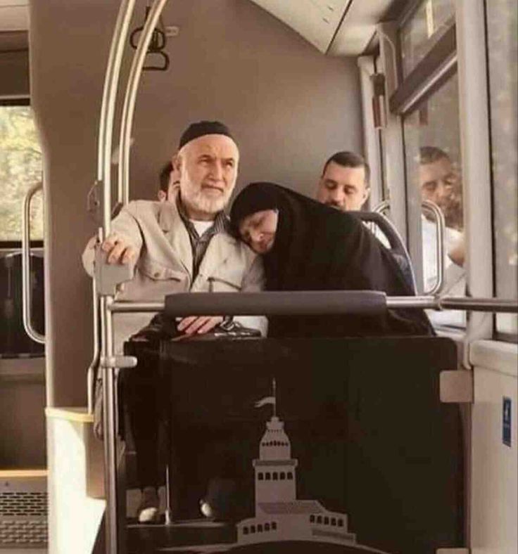 two men and a woman sitting on a bus looking out the window at another man