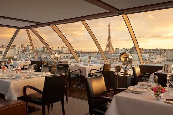 a dining area with tables and chairs overlooking the eiffel tower