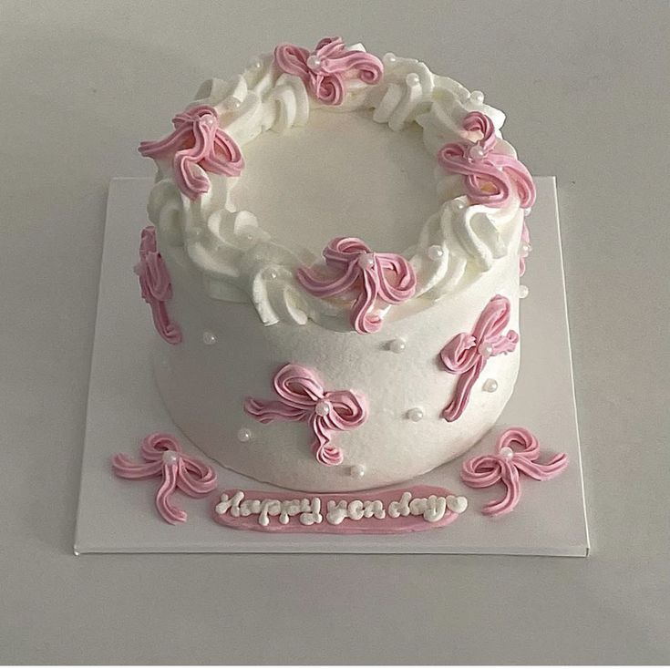 a white cake with pink bows and happy birthday written on it