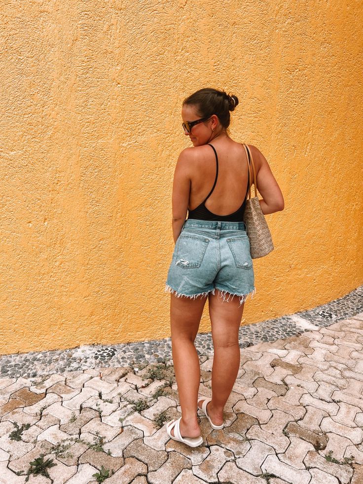 a woman standing in front of a yellow wall with her back turned to the camera