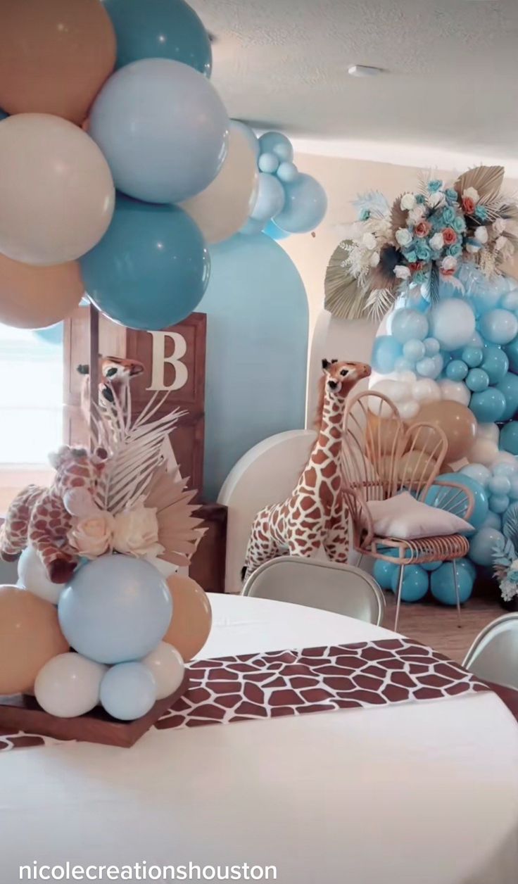 a giraffe themed birthday party with balloons and decorations in blue, beige and white colors