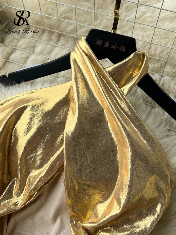 a shiny gold purse sitting on top of a white furnishce covered floor next to a black bag