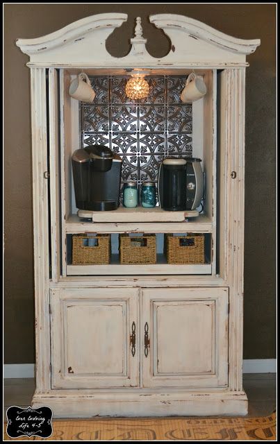 an old white china cabinet with baskets on the top and bottom shelf, in front of a brown wall