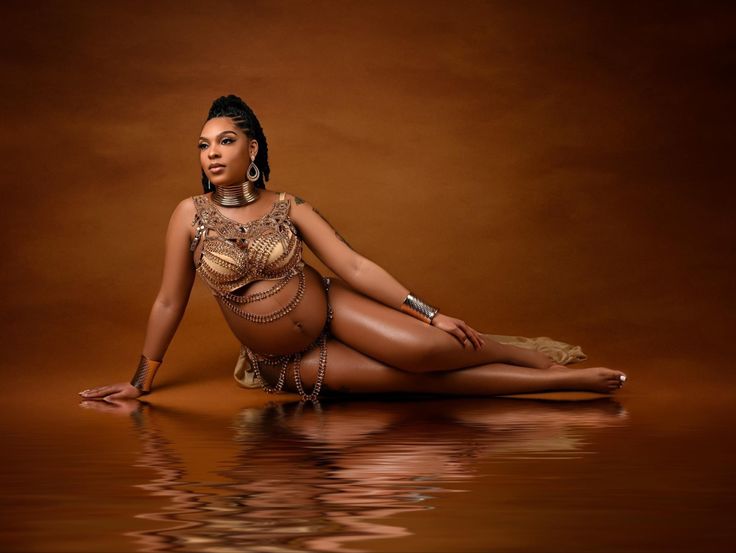 a woman is sitting on the floor in a gold outfit with chains around her ankles