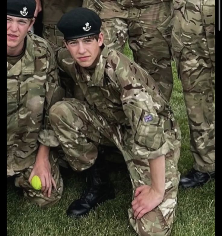 some soldiers are posing for a photo with a ball in their hand and one is holding a tennis racket