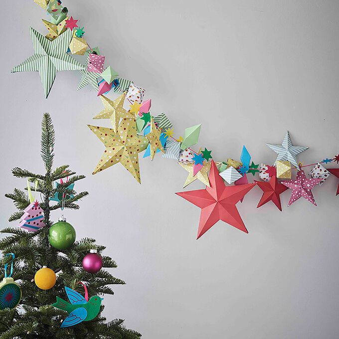 a christmas tree with paper stars hanging from it's sides next to a wall