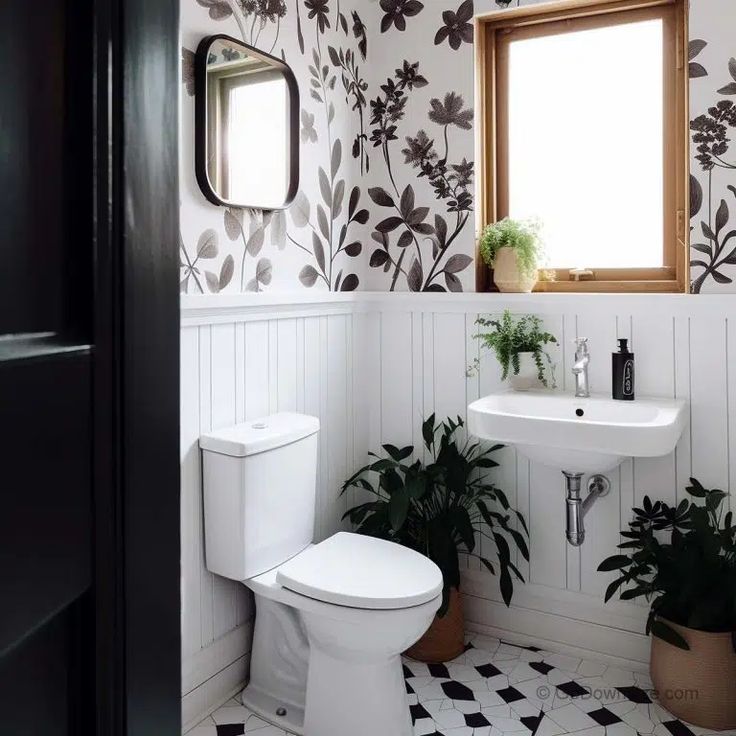 a white toilet sitting next to a sink in a bathroom under a window with black and white wallpaper