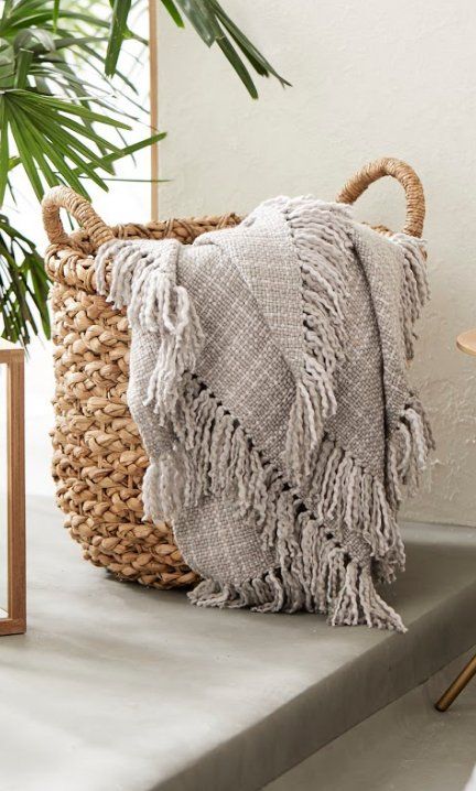 a woven basket sitting on top of a table next to a potted palm tree