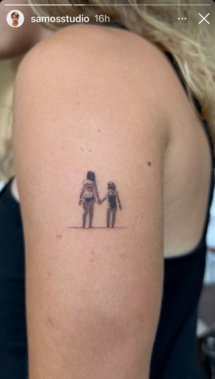 a woman with a small tattoo on her arm holding the hand of another person's shoulder