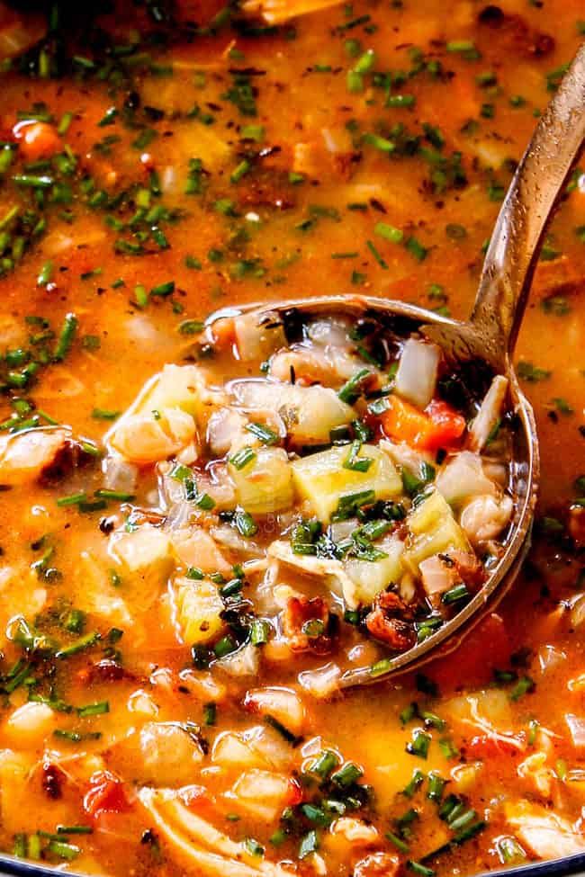 a ladle full of soup is being held by a wooden spoon