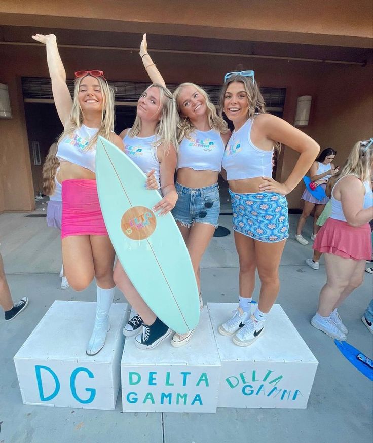 three girls in bathing suits are posing with a surfboard