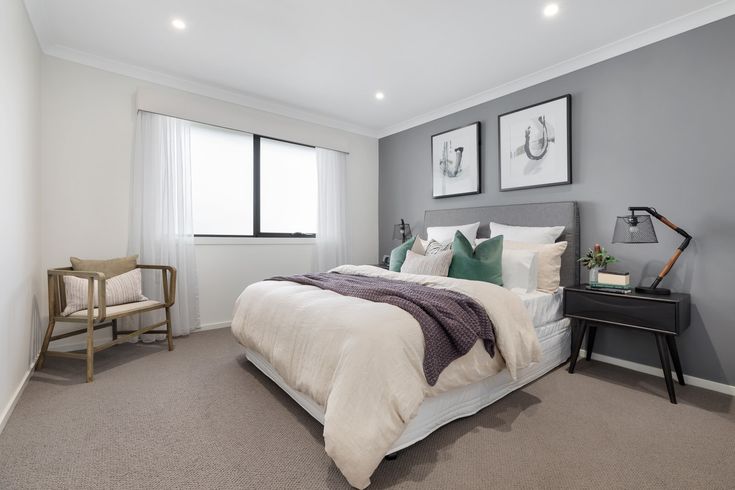 a bedroom with gray walls and white bedding, two framed pictures on the wall