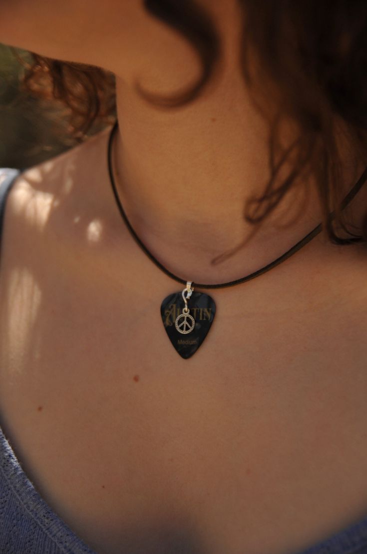 a woman wearing a black necklace with a peace sign pendant hanging from it's neck