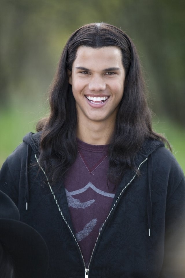 a young man with long hair smiling at the camera