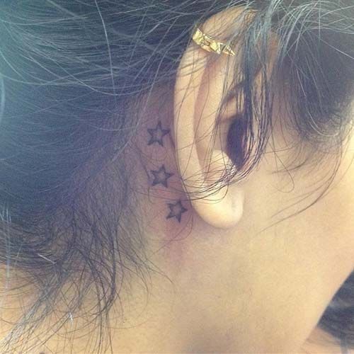 the back of a woman's ear with three stars on her left side behind it