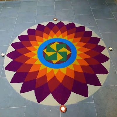 a colorful flower design on the ground in front of a tiled floor with several candles around it