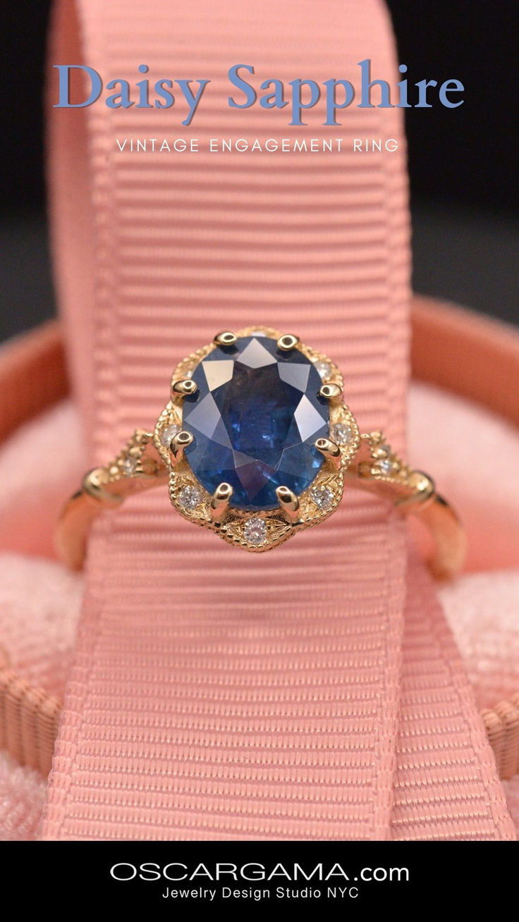 an engagement ring with a blue stone in it on top of a pink cloth box