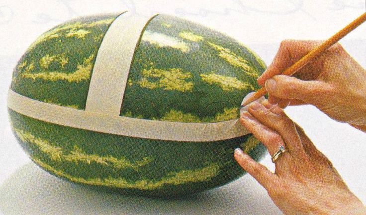 a person is painting a large watermelon with white tape