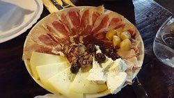 a plate with meat and fruit on it sitting on a table next to silverware