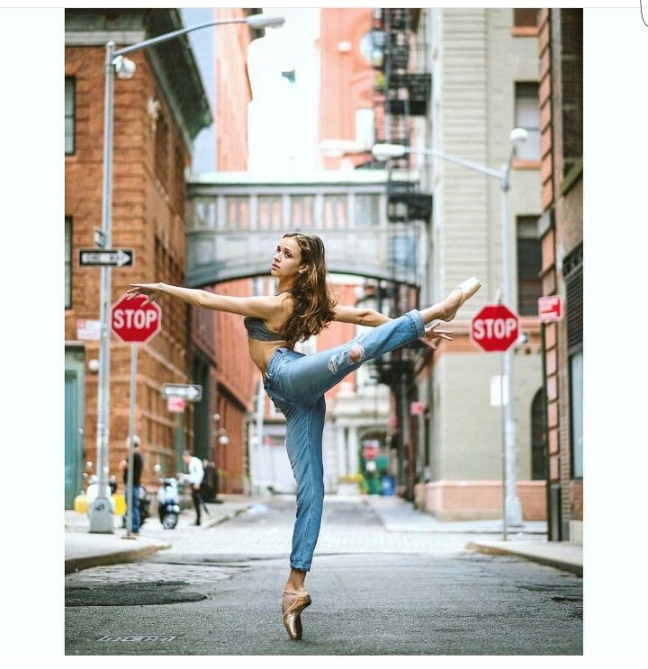 a woman is dancing on the street in front of stop signs