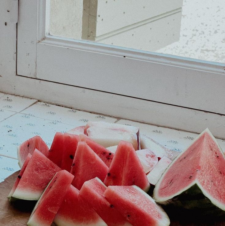 slices of watermelon on a cutting board next to a window