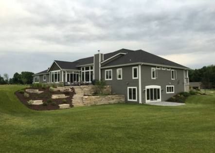 a large gray house sitting on top of a lush green field