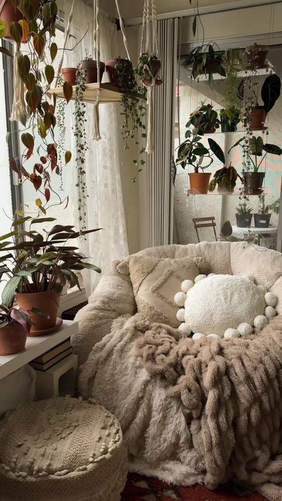 a living room filled with lots of plants next to a window and potted plants