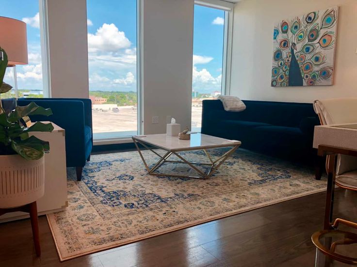 a living room with blue couches and large windows overlooking the beach in front of it