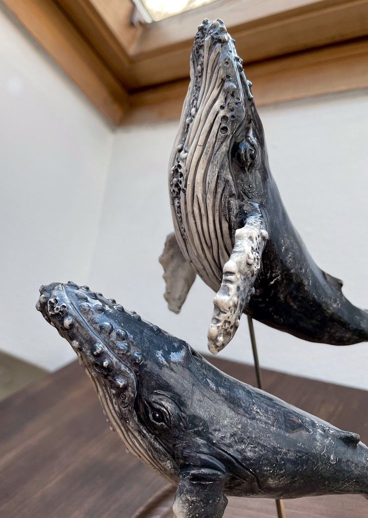 two sculptures of whales on display in a room