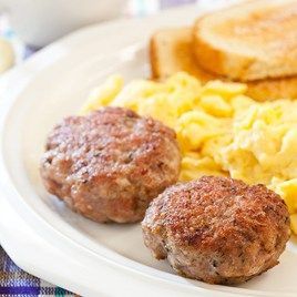 two meatballs and scrambled eggs are on a white plate with toasted bread,