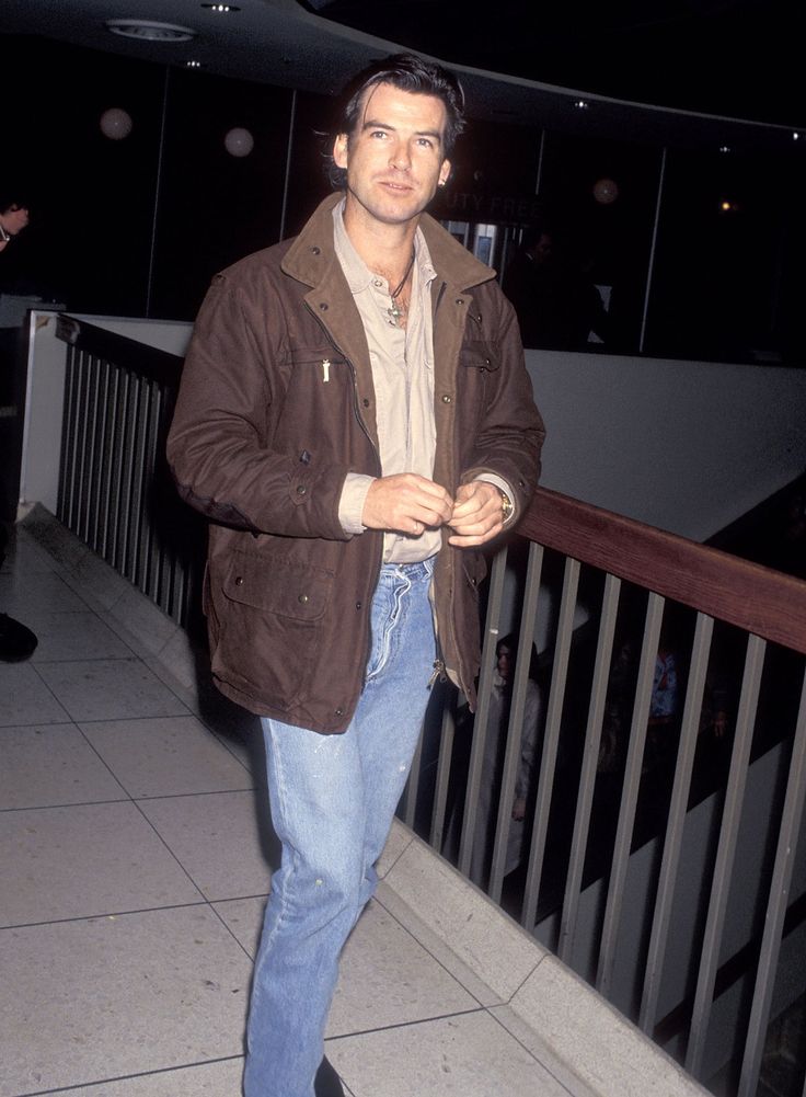 a man standing on the sidewalk in jeans and jacket