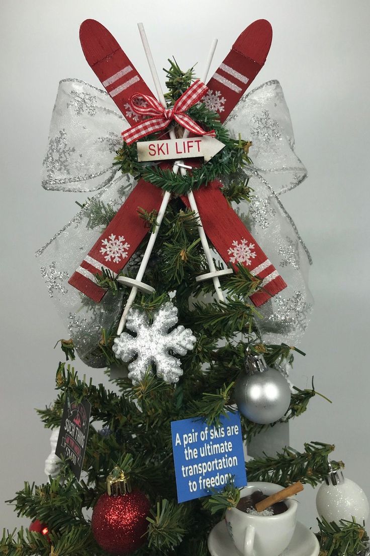 a christmas tree decorated with red and white ribbons, snowflakes, and skis