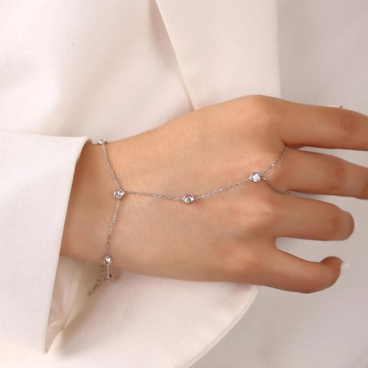 Add some sparkle to your everyday look! Delicate and elegant, this hand chain features zirconia crystals that will catch the light and shine with every movement. Perfect for dressing up any outfit, or as a unique addition to your jewelry collection. Metal: 925 sterling silver Finish: 18k gold Gemstone: white zirconia Bracelet length: adjustable with 4 cm extender (1.5") Chain: cable link Clasp: spring ring Hypoallergenic & nickel-free Don’t forget, proper care of your gold-plated jewelry will pr Delicate Cubic Zirconia Bracelet For Party, Party Jewelry With Diamond White Adjustable Chain, Party Jewelry With Adjustable Chain In Diamond White, Elegant Crystal Bracelet With Adjustable Chain, Wedding Crystal Bracelet With Adjustable Chain, Diamond White Jewelry With Adjustable Chain For Party, Elegant Cubic Zirconia Chain Ring Gift, Diamond White Party Jewelry With Adjustable Chain, Adjustable Chain Round Bracelet For Party