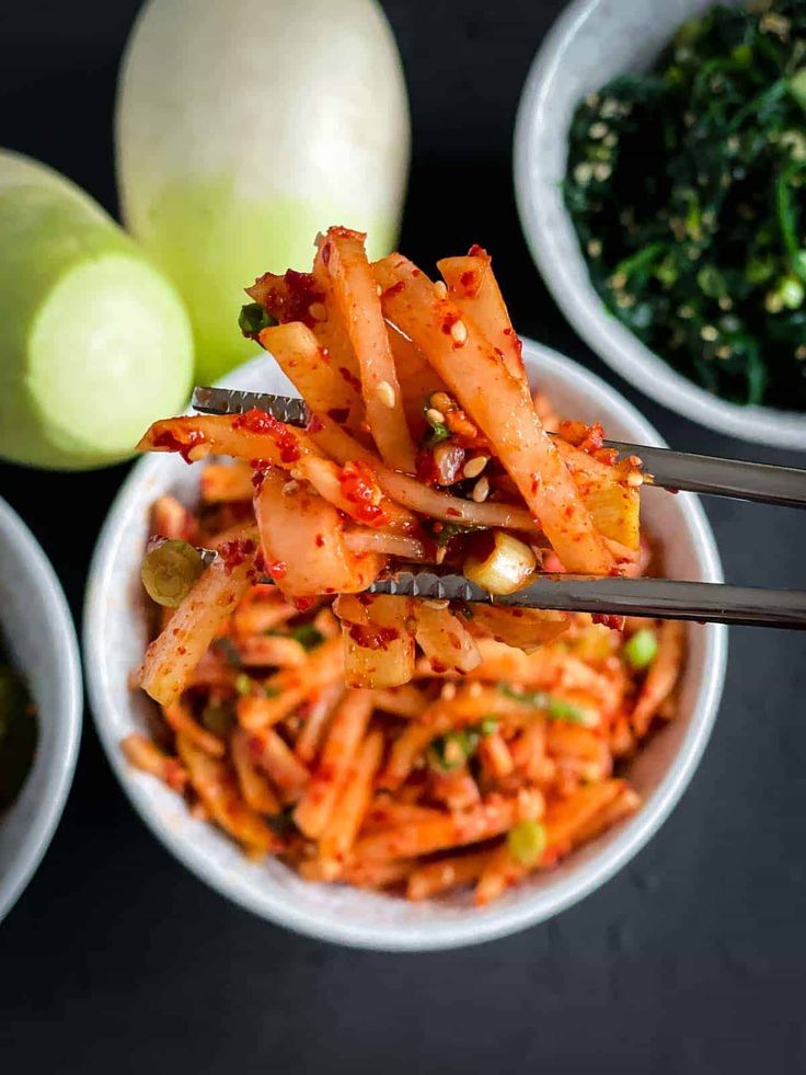 two bowls filled with noodles and vegetables next to some chopsticks in each bowl