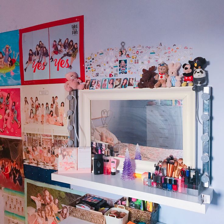 there are many pictures on the wall above the mirror and in front of it is a shelf with various items