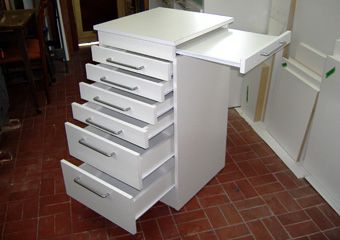 a white cabinet with five drawers on the bottom and four doors on the top, in front of a brick floor