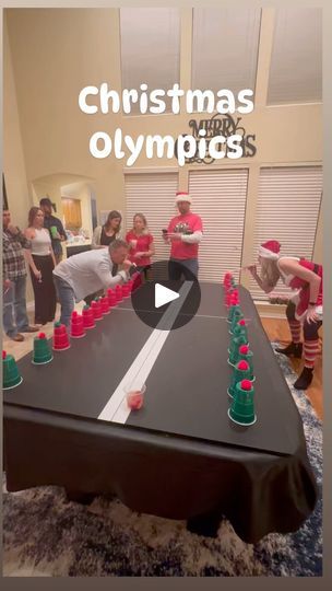 a group of people standing around a table with cups on it and the words christmas olympics in front of them