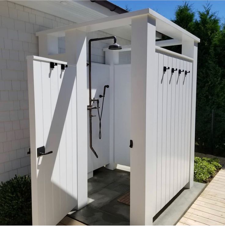 the outside of a white shed with two doors and an open shower stall in it